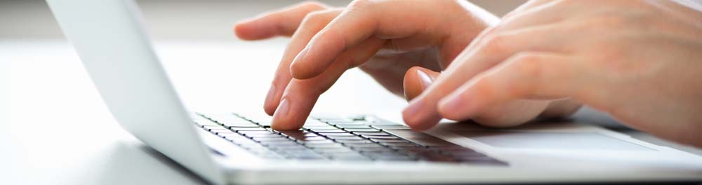 Hands typing on laptop